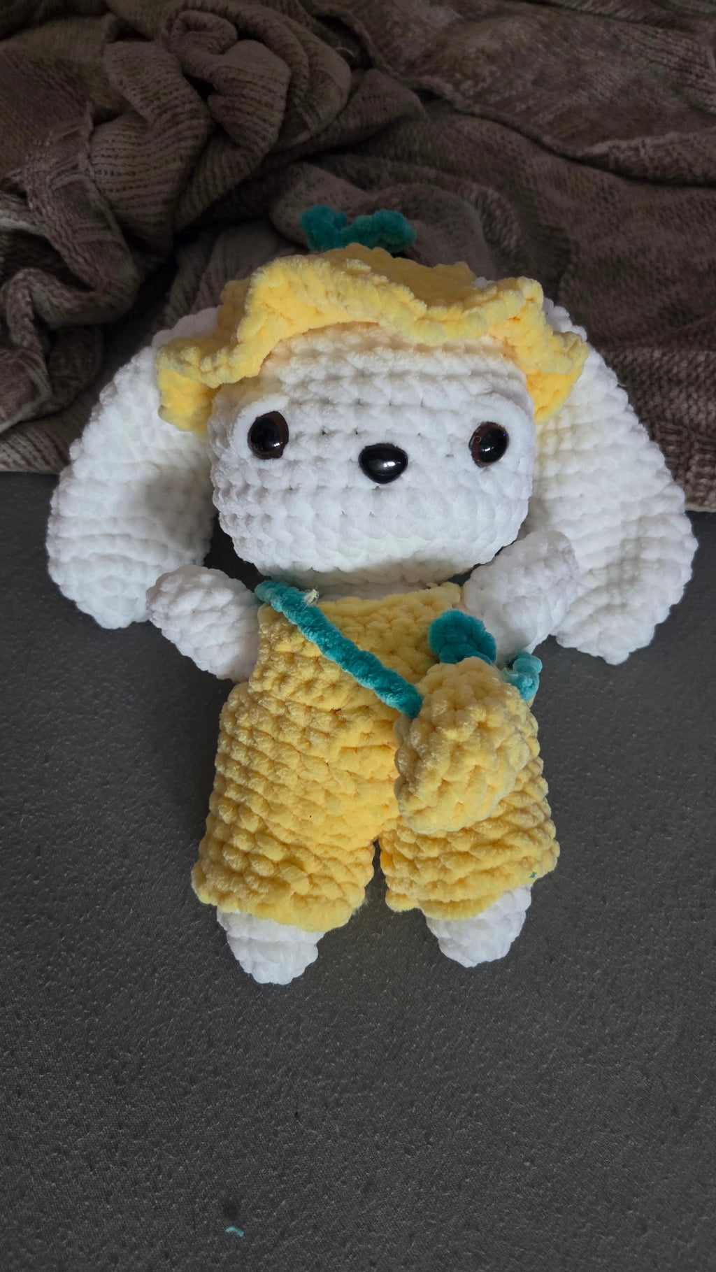 BrainRotPop handmade crochet bunny plushie wearing yellow dungarees, a sun hat, and a small cross-body bag.